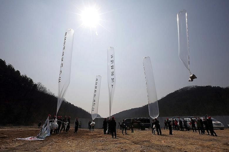 South Korean conservative activists launching large balloons carrying anti- Pyongyang leaflets at a field near the Demilitarised Zone dividing the two Koreas in Paju yesterday. The group sent the tens of thousands of leaflets criticising the North's 