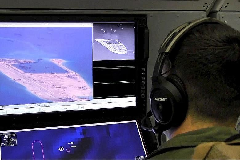 A US Navy crewman viewing a screen purportedly showing Chinese construction on a reef in the South China Sea in an image released last May.