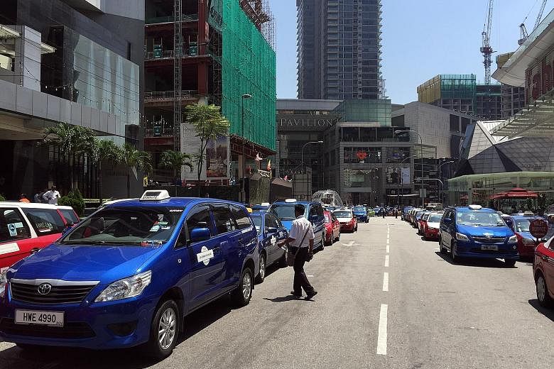 Taxis lining the street outside Pavilion shopping centre in Jalan Bukit Bintang in Kuala Lumpur yesterday, blocking the main road into the area. The police moved in to arrest five protesters and towed away the cabs that had not budged after a warning