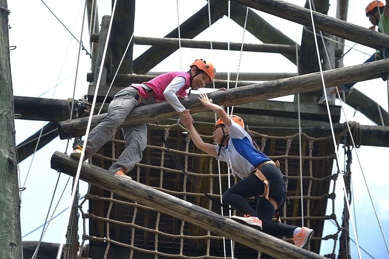 Minister for Culture, Community and Youth Grace Fu giving 15-year-old Lisa Giam of Kranji Secondary School a helping hand on the 18m-high Inverse Tower at Outward Bound Singapore's (OBS) Pulau Ubin campus yesterday. Announcing OBS' expansion to a new
