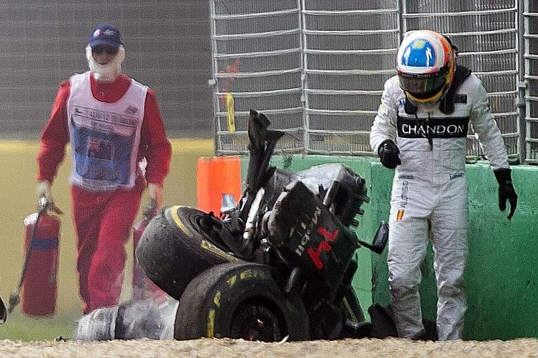 Fernando Alonso (right) walks away from his car after the crash at the Australian Grand Prix in Melbourne on March 20. He will not race in Bahrain after failing a medical test.