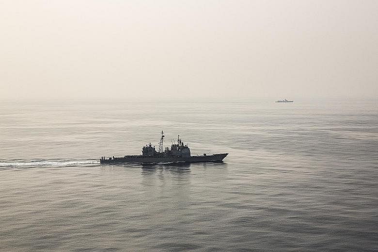 A Chinese warship (in background, right) following the USS Chancellorsville as it sailed through the South China Sea on Wednesday last week. The US Navy craft was shadowed until midnight on Thursday last week, when the American vessel exited the disp