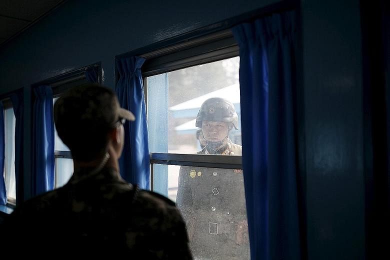 North and South Korean soldiers eyeballing each other at the truce village of Panmunjom yesterday. The two sides are technically still at war since their 1950-53 conflict ended in an armistice, not a peace treaty.