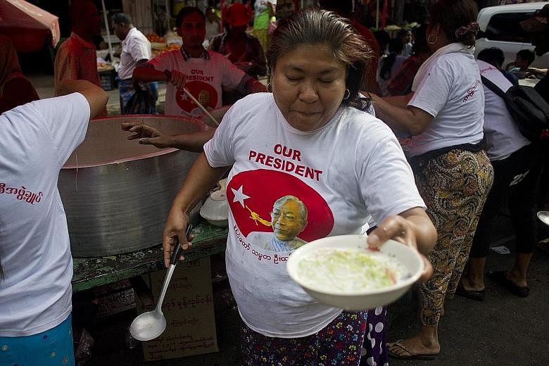 Supporters of the National League for Democracy (NLD) party offering free food during a street celebration to welcome President Htin Kyaw - Myanmar's first civilian president in 50 years - in Yangon yesterday. The South-east Asian nation was dominate