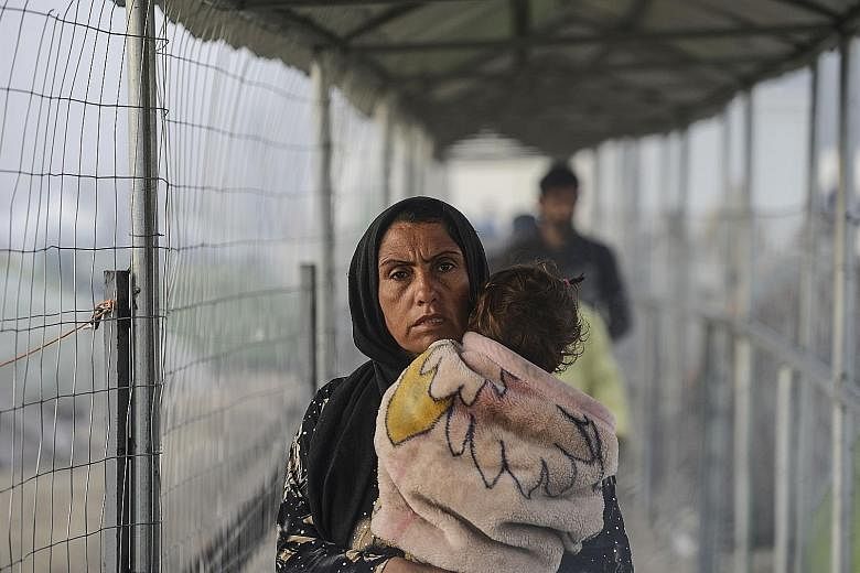 A migrant woman and child at a makeshift camp on the Greek-Macedonian border yesterday. Turkey says migrant returns from Greece to Turkey will start on Monday under its deal with the EU.