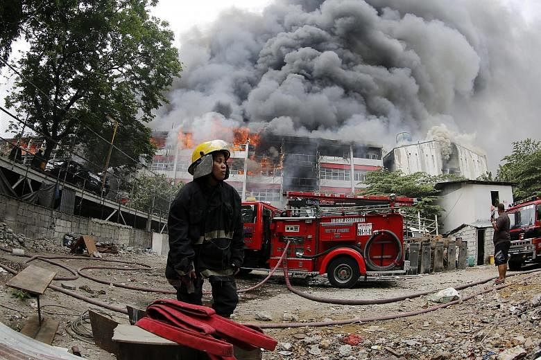 A firefighter at the scene of a massive blaze at the University of the East campus in Manila yesterday. Media reports say welding work at the College of Arts and Sciences building may have sparked the fire, which spread to two other buildings. Studen