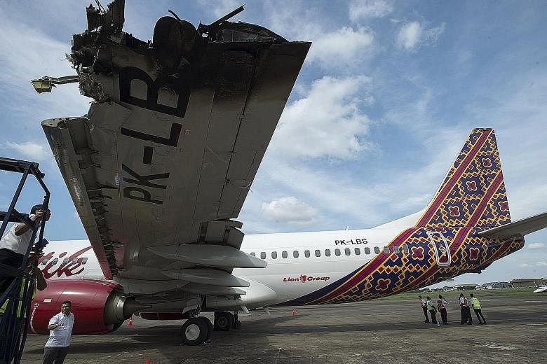Officials and investigators from the Ministry of Transportation examining the wing of a Batik Air Boeing 737-800 damaged in a collision on Monday with another plane while on the runway at Halim Perdanakusuma airport in Jakarta, Indonesia. The Transpo
