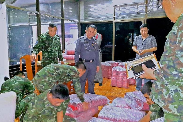 Soldiers and police officers (above) seizing allegedly "seditious" water bowls (left) from the house of a former MP in Thailand's Nan province. The bowls bearing well wishes from former premier Thaksin Shinawatra were meant as gifts to supporters for