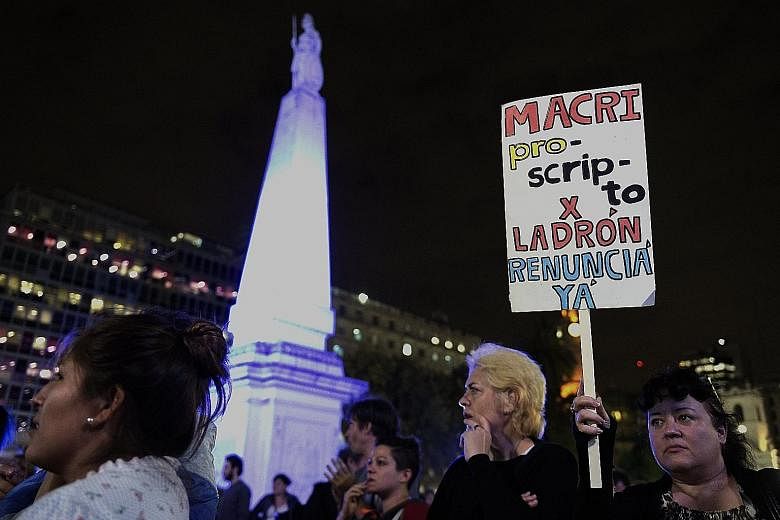 A protester with a sign reading "Macri outlaw for thief. Resign now" during a demonstration in Buenos Aires against President Mauricio Macri over his offshore financial dealings leaked in the Panama Papers.
