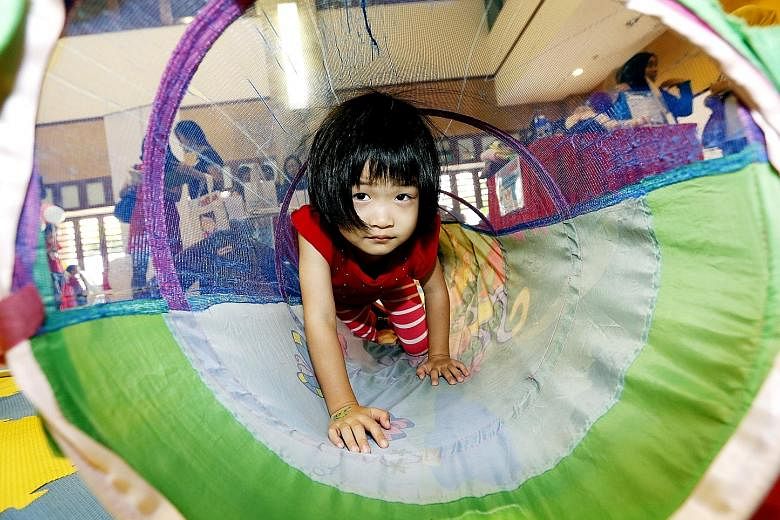 Four-year-old Lim Zi Wei crawling through a play tunnel at the annual Baby Singapore fair at the Fuchun Community Club yesterday. She was among 55 other toddlers and babies there with their parents. The little children, who are between six months and