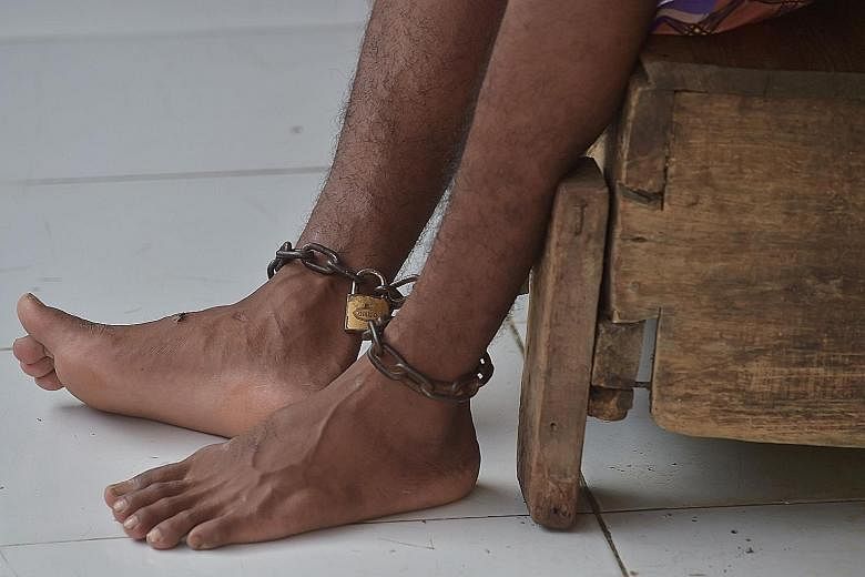 A patient (above) with mental illness at Galuh Rehabilitation Centre in Bekasi. Over 18,000 Indonesians with mental illness are either shackled (left) or locked up in a confined space, a practice known as "pasung".