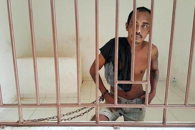 A patient (above) with mental illness at Galuh Rehabilitation Centre in Bekasi. Over 18,000 Indonesians with mental illness are either shackled (left) or locked up in a confined space, a practice known as "pasung".