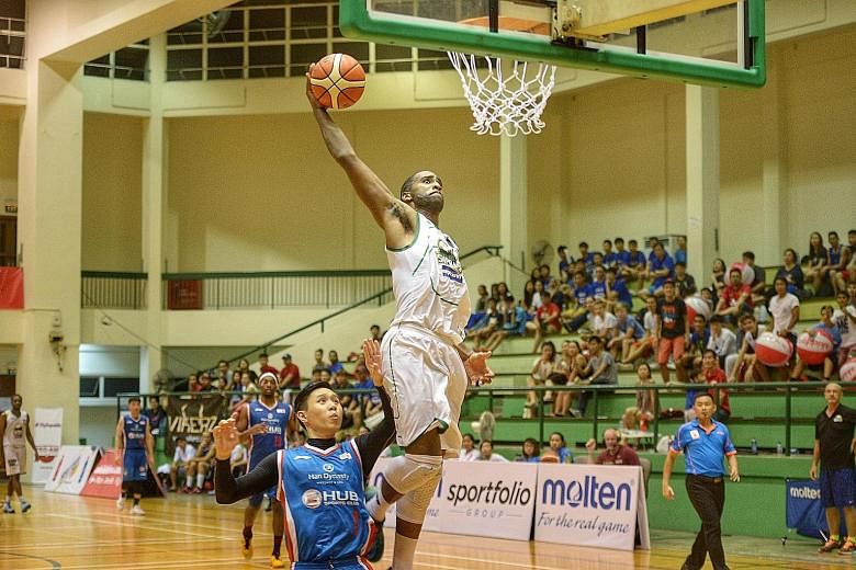 Singapore Supras forward Jemell Swafford (white) attempts a dunk after escaping the attention of GHUB Basketball's Leonard Ong (blue) at the Pro-Am Singapore Basketball League play-off finals at the Delta Sports Hall yesterday evening. Supras won 78-