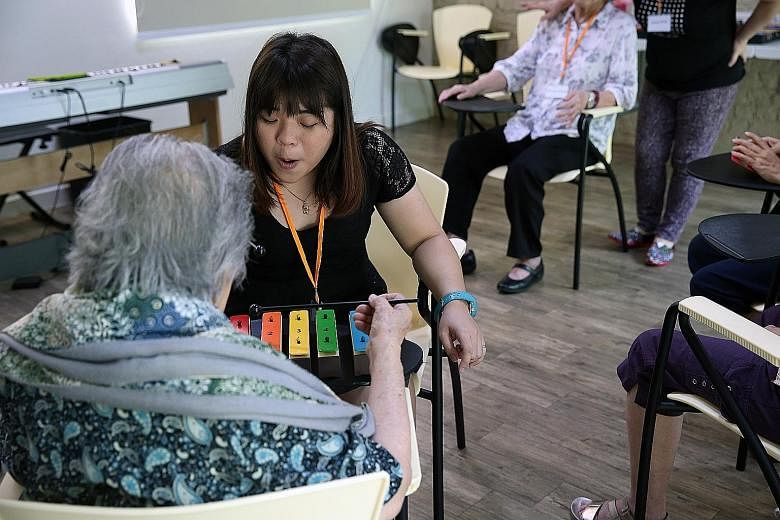 Music teacher Wan Hui Ling (left, in black) engaging a dementia patient on the xylophone as part of the music activities at the Montessori for Dementia Care centre in Upper Bukit Timah Road.