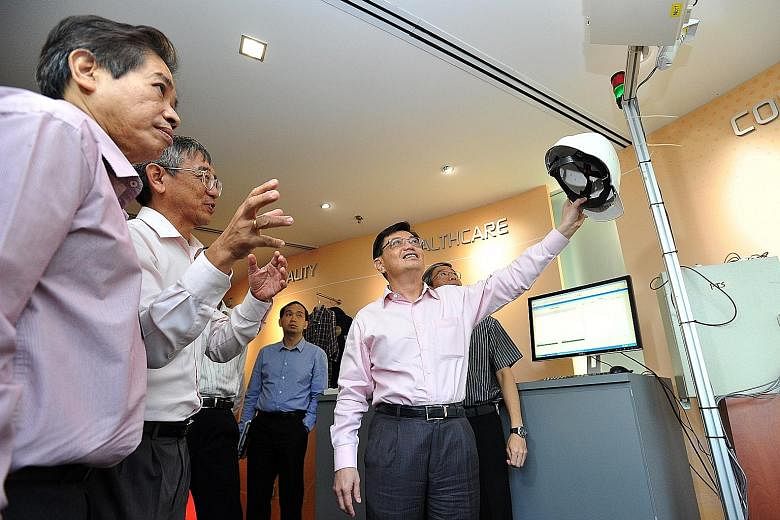 SIMTech executive director Lim Ser Yong (second from left) explaining the use of RFID-tagged helmets to Mr Heng during his visit yesterday. The RFID system was part of a project between SIMTech and the Land Transport Authority to track worker access 