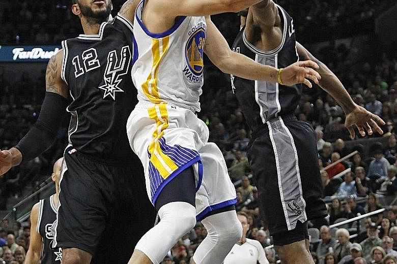 Golden State's Stephen Curry (centre) going up against San Antonio's LaMarcus Aldridge (left) and Kawhi Leonard at the AT&T Centre. The Warriors defeated the Spurs 92-86 on Sunday, tying the all-time record for wins in a season with 72.