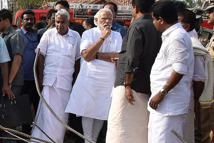 Indian Prime Minister Narendra Modi (centre) with Kerala Chief Minister Oommen Chandy (in white) beside him, at the site of the Puttingal Temple fire.