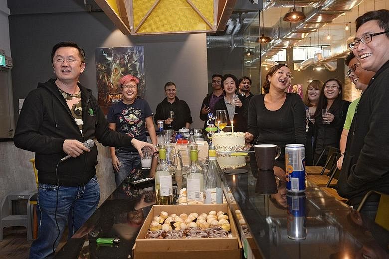 Founder and CEO of goGame David Ng (left) belting out a song on a karaoke machine during a birthday celebration for three of his employees at their Tai Seng Avenue office. The mobile game publisher's office has an industrial feel and a fully stocked 