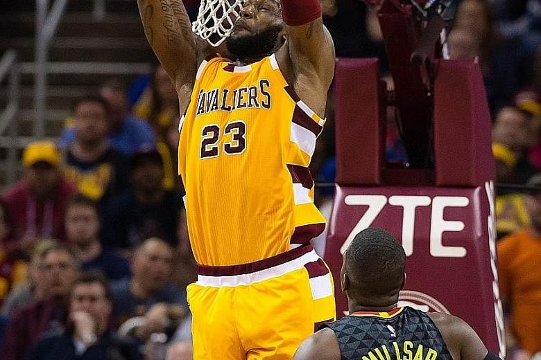 Cleveland Cavaliers forward LeBron James dunks over the Atlanta Hawks' Paul Millsap during the second half at the Quicken Loans Arena in Cleveland, Ohio. The Cavaliers won 109-94 to clinch top spot in the East.