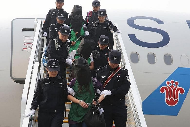 Suspects being escorted off a plane at Beijing airport yesterday after they were deported from Kenya.