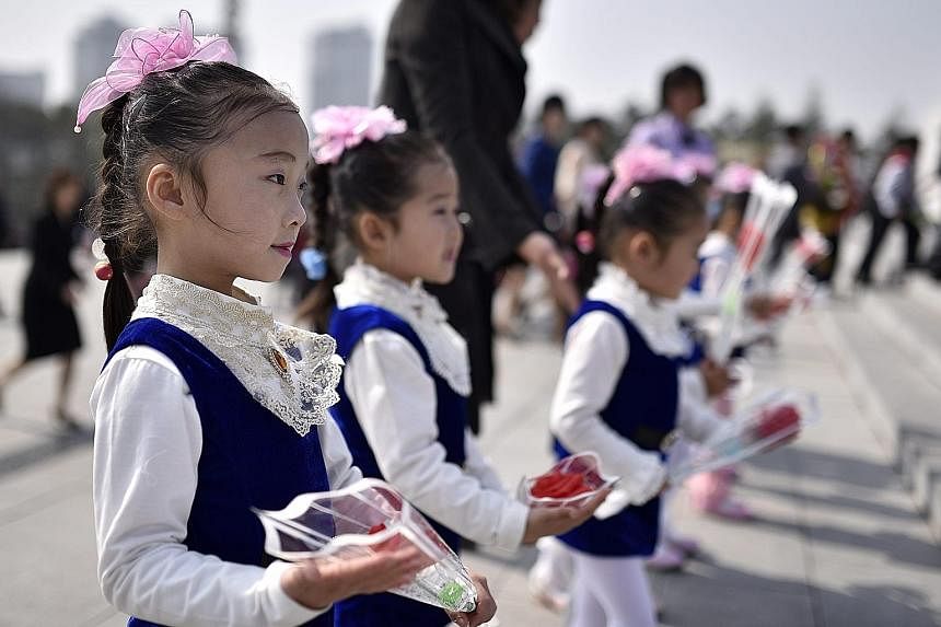 North Korean school children (above left) paying respects to the country's late founding father Kim Il Sung whose birthday was yesterday. Statues of Kim Il Sung (with raised hand) and his son Kim Jong Il outside Mansu Hill in Pyongyang on the Day of 