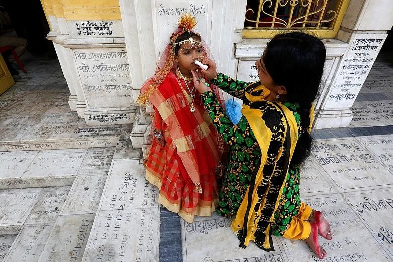 The mother of a young girl applying lip gloss on her daughter before the start of rituals to commemorate the Hindu festival called Navratri, at Adyapith temple on the outskirts of Kolkata, India, yesterday.