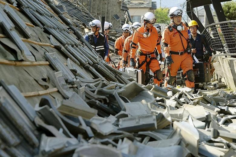 Firefighters looking for victims under collapsed houses in the aftermath of a magnitude-6.5 earthquake in Mashiki town, Kumamoto prefecture, in south-western Japan yesterday. The quake killed nine people, injured at least 1,000 and cut power and wate