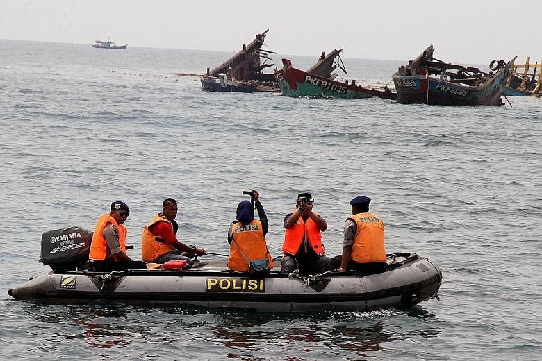 Police officers near the wreckage of illegal fishing boats blown up by Indonesian authorities in Kuala Langsa, Aceh province, earlier this month.