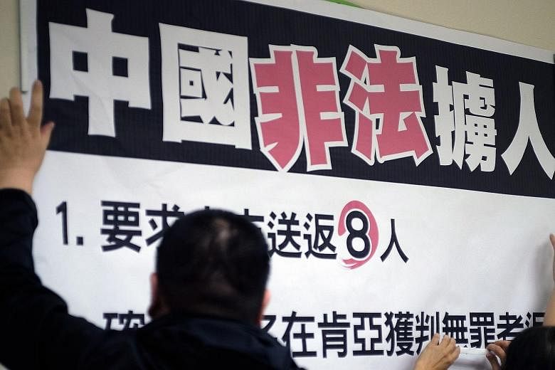 A sign saying "China illegally abducts Taiwanese people" being put up at a DPP media conference in Taipei on Tuesday. Several dozen Taiwanese arrested in Kenya for fraud were forced at gunpoint to board a plane for China on Monday.