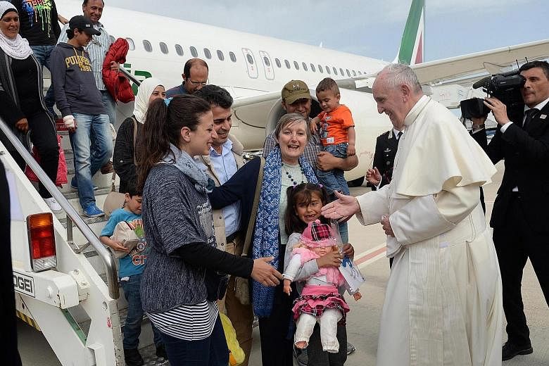 Pope Francis welcoming a group of Syrian refugees who flew in with him at Ciampino airport in Rome yesterday.