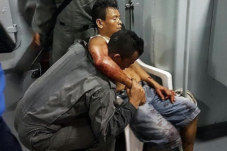 A member of the Malaysian Maritime Enforcement Force helping an Indonesian sailor who was shot while trying to resist capture by pirates, after the tugboat he was in was attacked in the South China Sea.