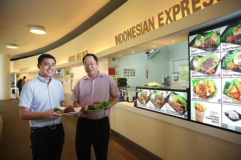 Mr Peh (far left) and Mr Ng with some of the healthier dishes available at their food stalls in NUS. Their stalls have joined HPB's Healthier Dining Programme, under which they receive help to come up with healthier meal options.