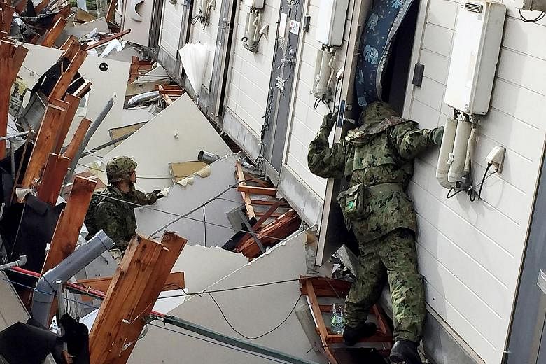 Soldiers searching for survivors yesterday in a collapsed apartment in the aftermath of two earthquakes in Minamiaso, Kumamoto prefecture. Heavy rains fuelled worries of more landslides and with hundreds of aftershocks and fears of more, thousands sp