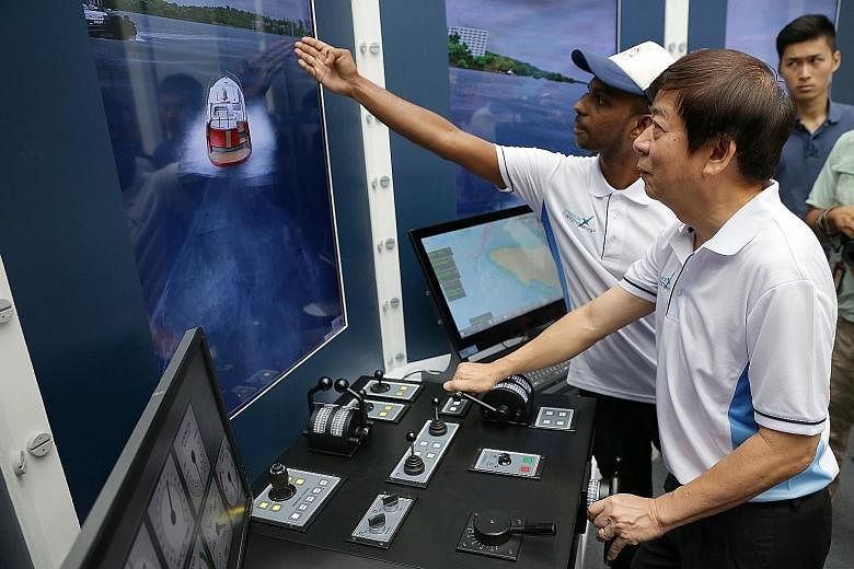 Mr Rajamohan Krishnan, 33, from the Singapore Maritime Academy, guiding Transport Minister Khaw on a ship simulator as the latter navigates a ship away from big vessels and berths it at the port successfully.