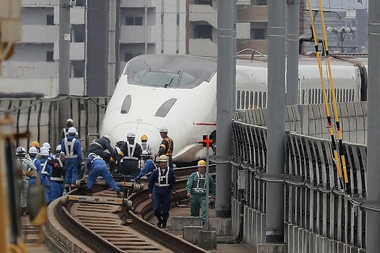 Railway workers yesterday attending to a Kyushu shinkansen (bullet train) after it became derailed during the quake in Kumamoto. At least 42 people are known to have died in the tremors.
