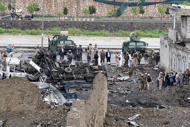 Afghan security officials inspecting the site of a suicide bombing in Kabul yesterday. Taleban militants, who last week launched their annual spring offensive, claimed responsibility for the attack. A girl injured in yesterday's suicide bomb blast in