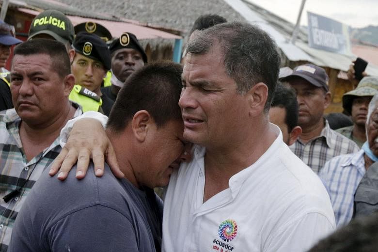 President Correa comforting a resident in the town of Canoa, Ecuador, on Monday. People have taken to looting, taking things such as clothes, shoes, aluminium window frames and cables, in hopes of selling the materials. Economic growth forecasts are near 