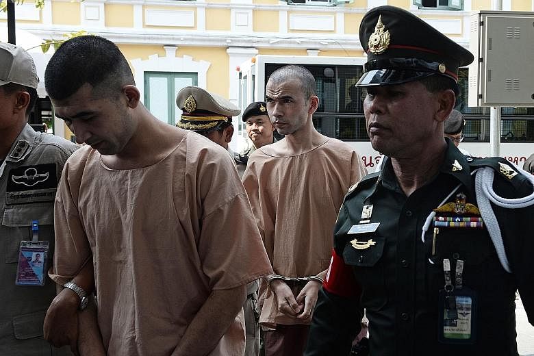 Mieraili (left) and Karadag (centre) under police escort at a military court in Bangkok yesterday. Both are Uighur Muslims. Police have issued arrest warrants for 15 other people in connection with the Aug 17 blast.