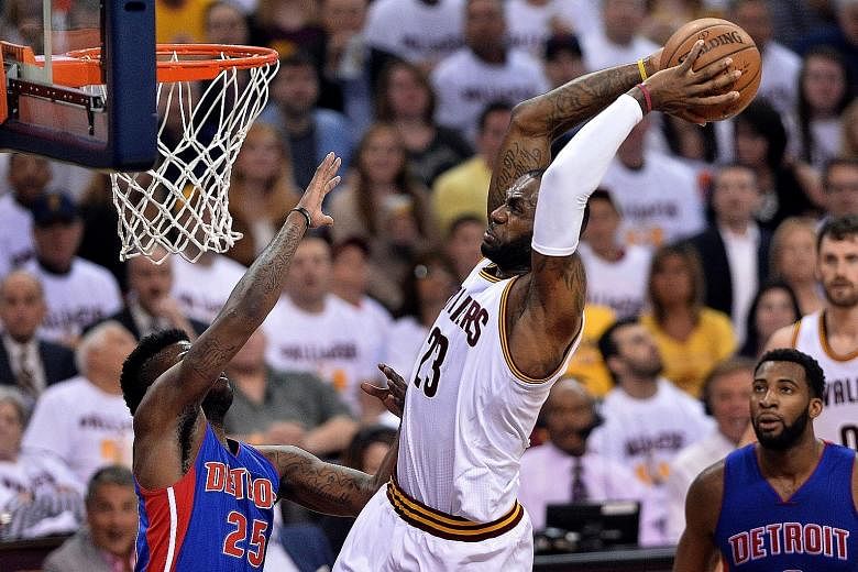 Cleveland's LeBron James (23) slam dunks over Detroit's Reggie Bullock during the Cavs' 107-90 victory on Wednesday. The Pistons had no answer to James' power and great three-point shooting from J.R. Smith, Kyrie Irving and Kevin Love.