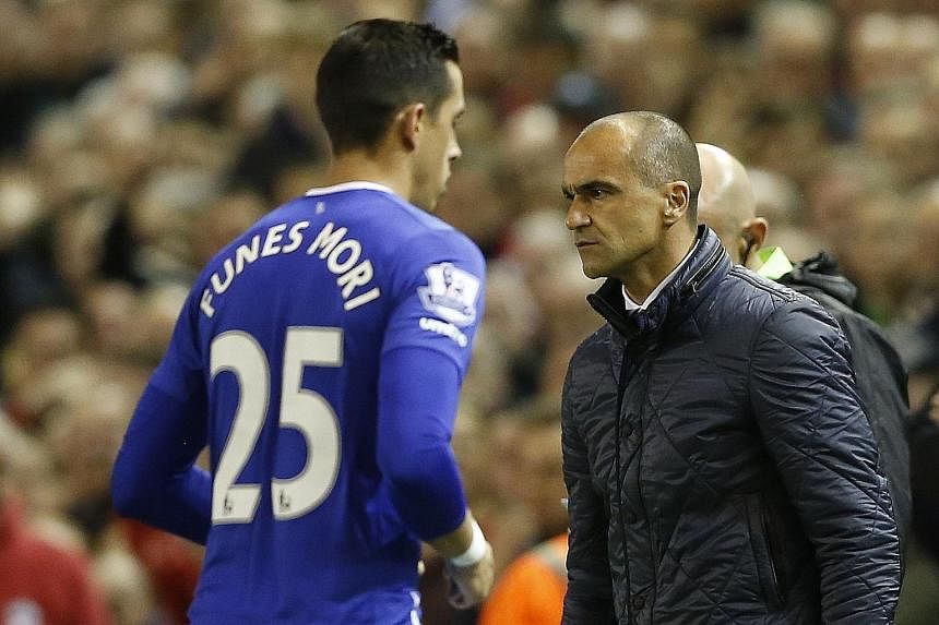 Defender Ramiro Funes Mori walking past an angry Everton manager Roberto Martinez after being sent off for a bad tackle on Divock Origi.