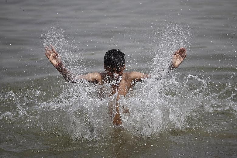 A boy cooling off in the Yamuna river in New Delhi yesterday. Temperatures have soared beyond 40 deg C this month, early for a country that usually records its highest temperatures in May and June.