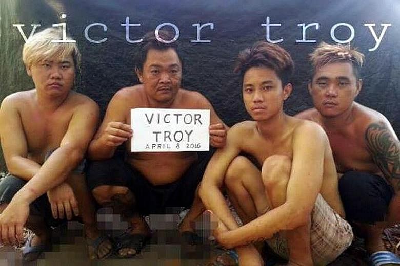The four Malaysians said to have been kidnapped by the Abu Sayyaf on April 1. "Victor Troy" in the sign refers to a Facebook account under the name "Victor Troy Poz", where the image was first loaded. Police are investigating the account's owner.