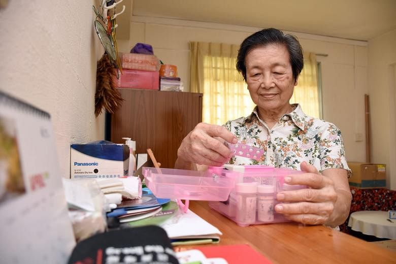 Madam Chan Soh Mui, 82, with a medicine box that has a sensor on its cover to detect when she opens it. Passive infra-red sensors were also installed on the walls to track her movements. 