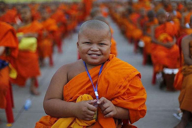 A novice posing for a picture yesterday while monks gathered to receive alms at Wat Phra Dhammakaya temple, in what organisers said was a meeting of 100,000 monks in Pathum Thani, outside Bangkok.