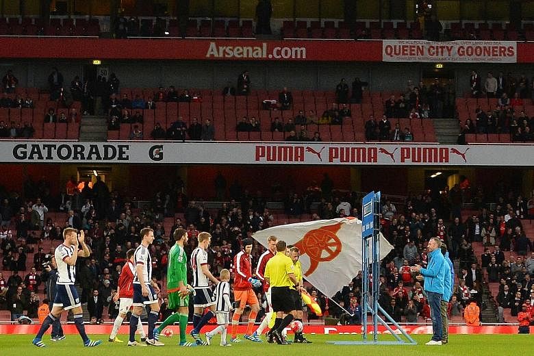 Empty seats are visible at the Emirates Stadium as the players come on to the pitch during the Premier League match between Arsenal and West Bromwich Albion on Thursday. There is a growing disenchantment among Arsenal supporters about the team's disa