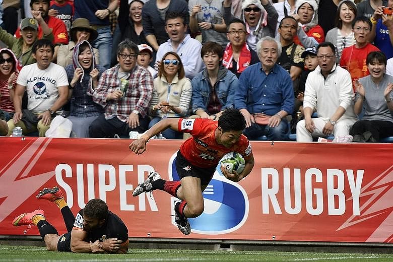 Yasutaka Sasakura (left) scoring the first of the Sunwolves' three tries against the Jaguares in their Super Rugby match at the Prince Chichibu Memorial Stadium in Tokyo yesterday, while the team (above) celebrate their maiden victory.