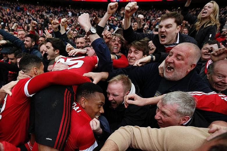 Almost engulfed by a sea of jubilant Manchester United supporters, striker Anthony Martial celebrates after scoring the 93rd-minute winning goal at Wembley in the dramatic 2-1 victory against Everton on Saturday to put his team into the FA Cup final.