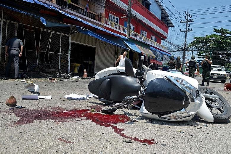 Members of the Thai bomb squad inspecting the site of a motorcycle bomb attack which injured 13 people, including five police officers and a young girl, in Thailand's southern province of Narathiwat yesterday. The bomb was one of two hidden in motorb