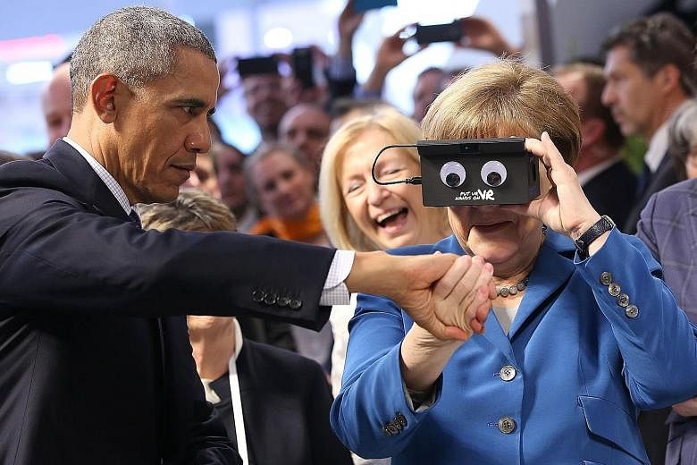 Mr Obama giving Dr Merkel a hand as she tried on a virtual reality device made by German automation company ifm electronic at a trade fair in Hanover yesterday. At the end of a six-day foreign tour, the US leader made an impassioned plea for European