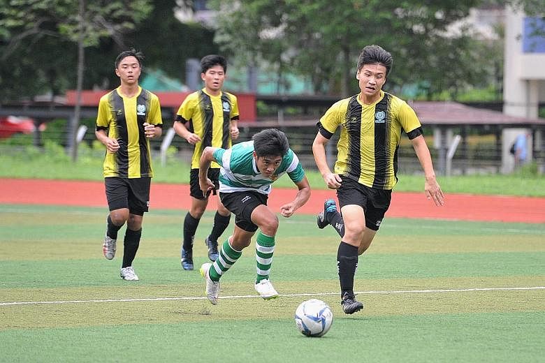 Raffles Institution's Jonathan Chua (green jersey) battling for possession against Temasek Junior College players during their 3-1 win yesterday, which ensured that RI move on to the Schools National A Division semi-finals.